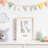 Stylish scandinavian newborn baby room with toys, teddy bear, accessories, ,cloud,colorful cotton flags and natural basket. Modern interior with mock up photo or poster frame. Real photo. Template.